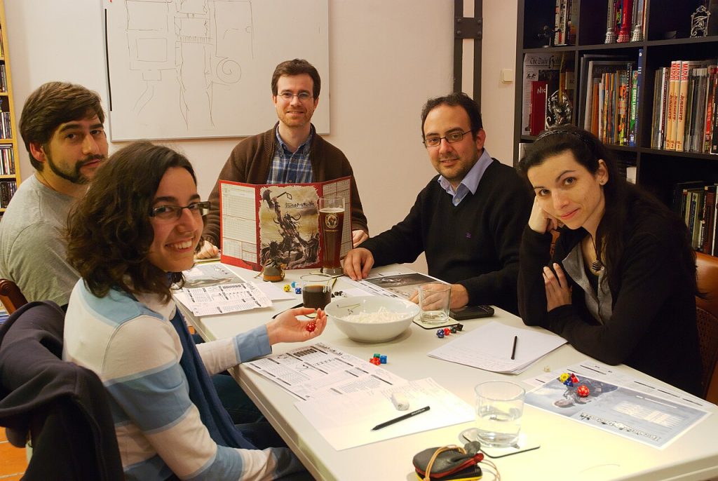Grupo de jugadores prepara una partida de rol de mesa con dados, hojas de personaje y pantalla del director.